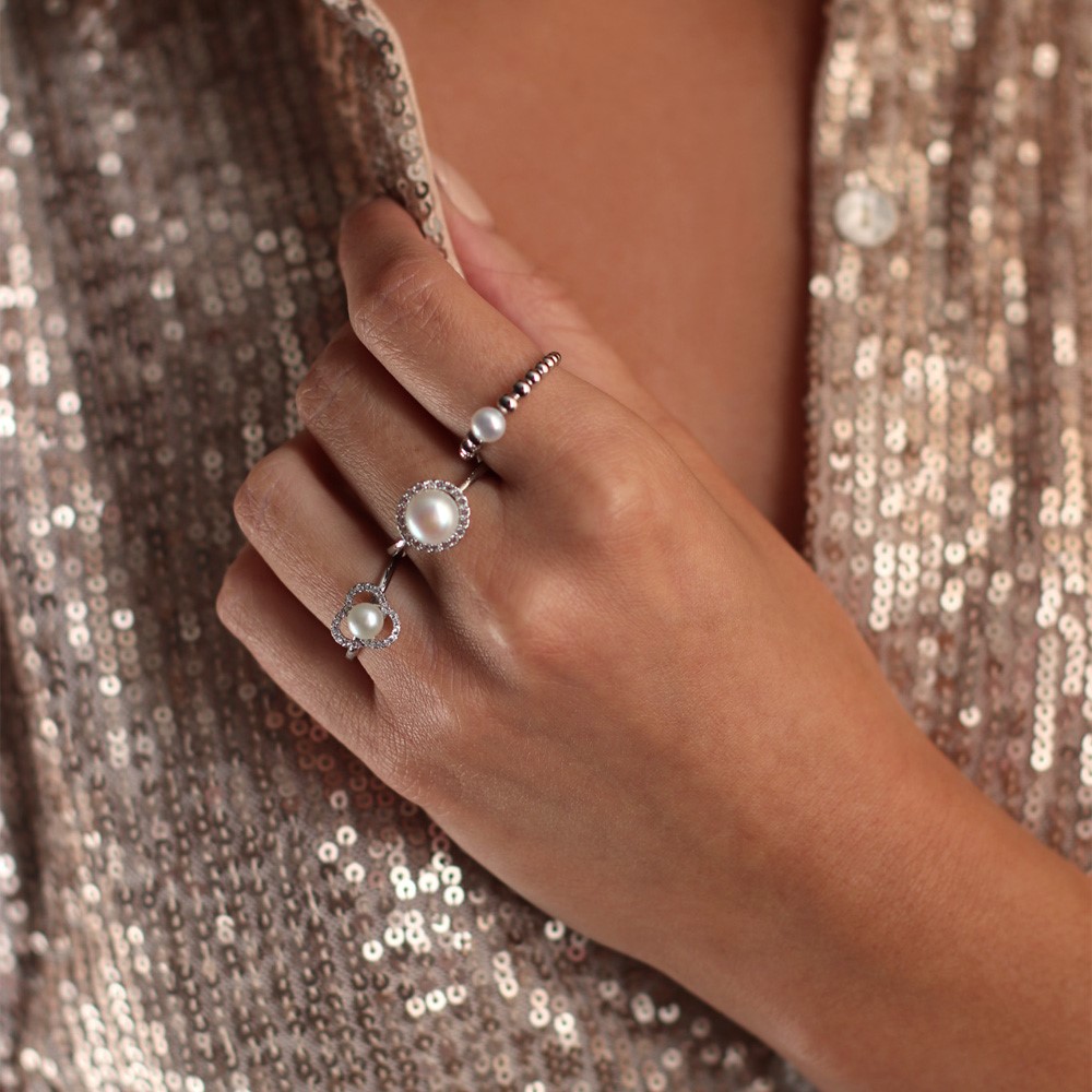 A Lady wearing 3 Isle of Wight Pearl Rings, one being from their Amberley collection featuring a freshwater pearl, white topaz on rhodium plated sterling silver
