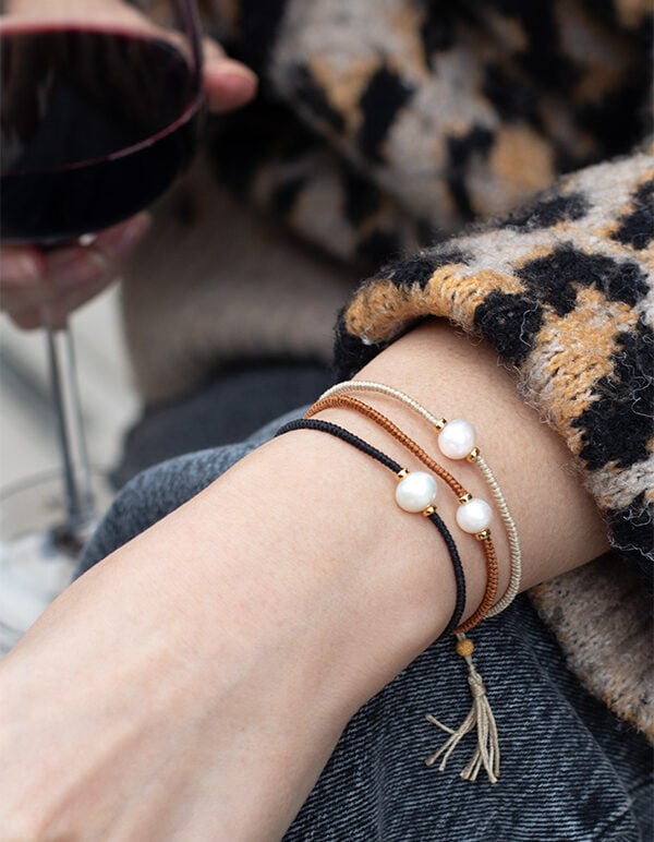 model wearing 3 brown and tan coloured tassel pearl bracelets